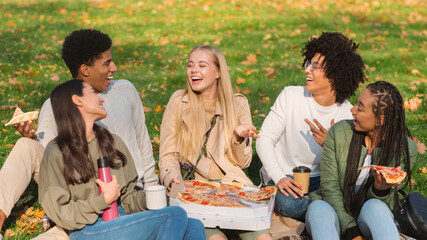 Cheery international students sharing their stories while eating pizza at park
