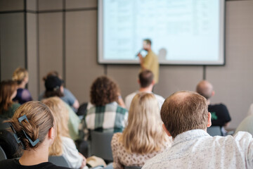 Man giving presentation to attentive group in conference room. Audience focused on speaker sharing insights and information during seminar.