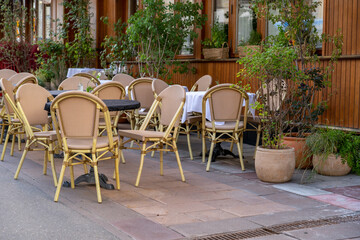 A charming outdoor dining area features empty tables and chairs amidst greenery in a peaceful neighborhood