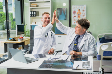 Obraz premium Caucasian middle-aged male doctor and Italian scientific researcher are seated at desk, discussing innovative antiviral drug inventions, with a monitor displaying the latest technology advancements.