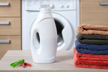 Close-up white plastic bottle with liquid washing gel into the container of a washing machine.
