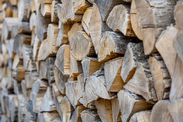 Naklejka premium Background of stacked chopped wood logs. Pile of wood logs ready for winter. Wooden stumps, firewood stacked in heap