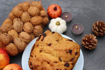 Raisin fruit cake dessert traditional pastry dried fruits, nuts, apples, cones and candles on dark grey background with copy space. Autumn menu ideas. 