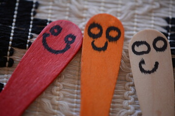 Colorful happy faces on ice cream wooden spoons.