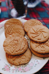 on the kitchen table on a tablecloth with New Year's decor there are gingerbread cookies in plates, preparing a gingerbread house photo with noise effect close up, focus on cookies