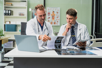 Obraz premium Caucasian middle-aged male doctor and Italian scientific researcher are seated at desk, discussing innovative antiviral drug inventions, with a monitor displaying the latest technology advancements.