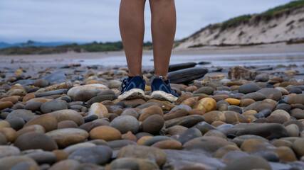 Pies de chica sobre playa de piedras