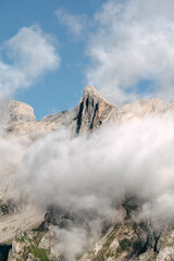 Majestic mountain peak shrouded in clouds under a clear blue sky