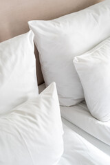 Crisp white bedding and pillows arranged neatly on a comfortable bed in a cozy room during daylight
