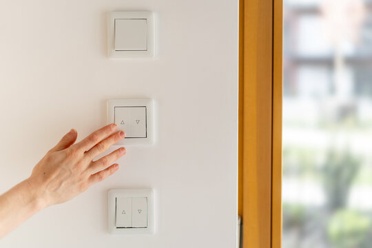 Hand reaching for a white light switch in living room