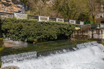 Spring mountain landscape with a bridge over a bubbling river cascade in Abkhazia, Georgia. Water flows out of the Blue Lake, a popular attraction on the way to Lake Ritsa