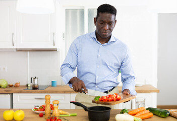 Smiling african american man eating apple in home kitchen