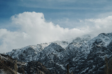 Panoramic view of snow-capped mountains against a blue cloudy sky.