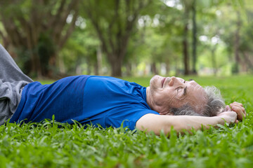 serene senior man lying down on grassess and taking a nap while resting in park,elderly...