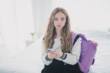 Portrait of sweet cute teen lady moody upset sit bed hold device wear trendy school uniform prepare...