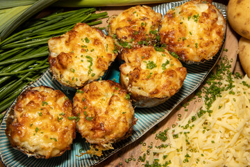 A selection of delicious Fish Pie Potato Skins topped with cheese and garnish on a wooden kitchen table background