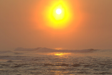 Bright reddish and orange light sunrise on the sea. Tropical beach of Itaguare, Bertioga, Brazil