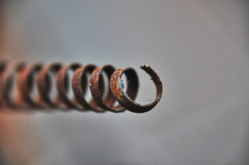 A metal sharp-ended spring covered in rust old metal