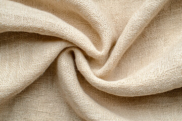 Close-up of beige linen fabric with a twisted center, showcasing its texture and woven pattern, perfect for textile and fabric design backgrounds.
