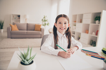 Photo portrait of cute small schoolgirl drawing pencils idea cheerful home education concept school interior