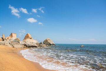 Rock Beach, Stone Sea bay with blue sky white clouds background on daylight in summer and white foamy wave on sand beach seaside vacation well space for text