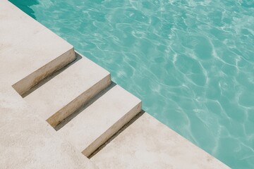 Obraz premium beige steps descending into light turquoise swimming pool water, modern poolside design