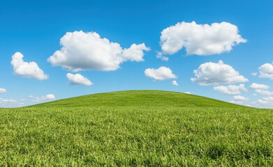 Naklejka premium Green grassy hill under a blue sky with scattered white clouds, showcasing the serene beauty of nature and open space.