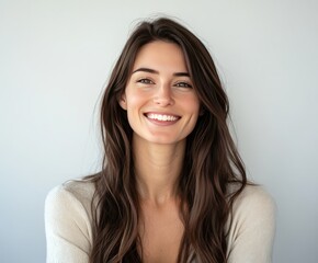 Fototapeta premium A smiling girl with long hair poses against a light background in a casual sweater