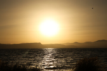 sunset at Sea of Galilee view to the city Tiberias mountains and birds fly above