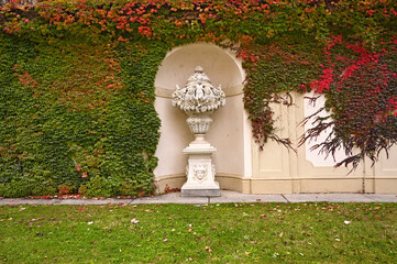 Old stone statue and wall cowered with creeper plant,autumn season, Vienna, Austria