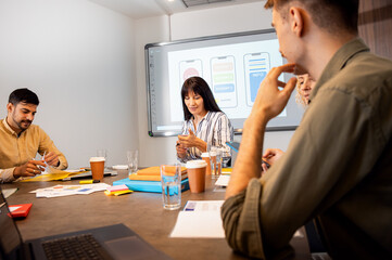 Group of business people sitting in a meeting room discussing a design for a smartphone application.