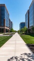 Fototapeta premium Modern office complex with striking glass facades surrounded by lush greenery under a clear blue sky