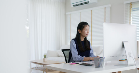 Young lady asia people teen girl talent workforce remote work at home office workspace sit relax on desk table. Distant job digital learn online reskill upskill career coding class chat on desktop PC.