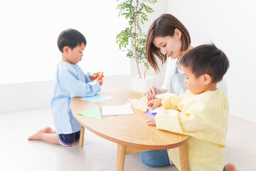 幼稚園で折り紙をする子どもと先生