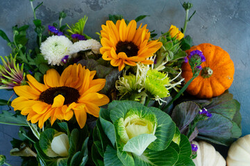 Bouquet of fall flowers and pumpkins on gray background