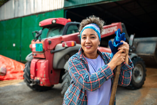 Portrait of a female farmer smiling in front of tractor on the farm