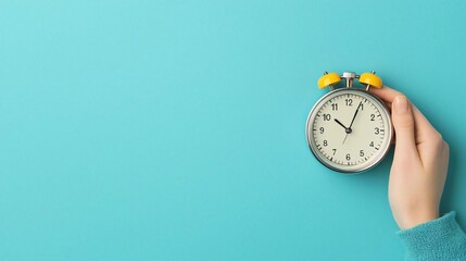 A close-up of a hand holding a vintage alarm clock against a vibrant turquoise background, symbolizing time management and urgency.