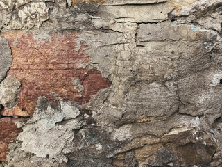 Fototapeta premium A wall with a lot of cracks and peeling paint. The wall is made of stone and has a rough texture