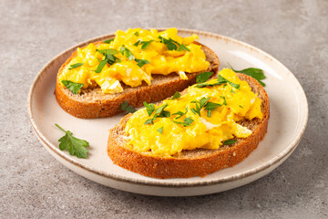 Scrambled eggs with green herbs on wheat-rye crispy toast.