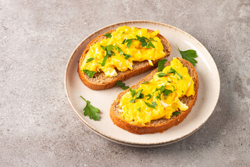 Scrambled eggs with green herbs on wheat-rye crispy toast.