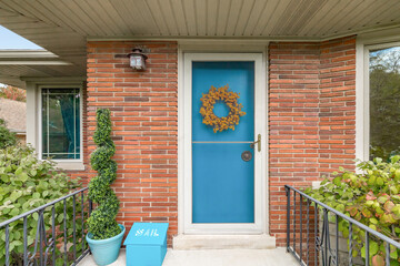 A front door detail with red brick siding, a light blue front door, and a covered porch.