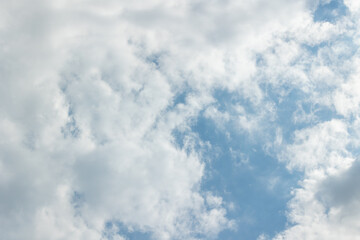 White clouds in a bright blue sky with sunbeams breaking through