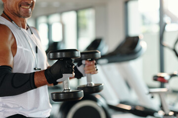 Muscular sportive man training with dumbbells in sport gym
