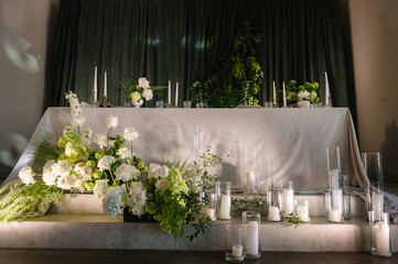 Wedding reception. Festive table decorated composition flowers and candles in hall restaurant. Table newlyweds covered tablecloth in banquet area at wedding party. Table setting. Celebration concept.