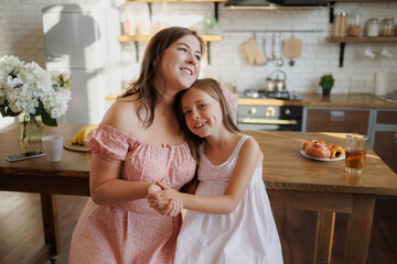 Smiling mother and child holding hands in kitchen in morning