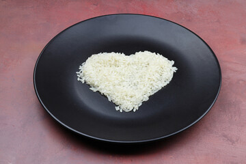 white rice in heart shape on black plate on wooden table