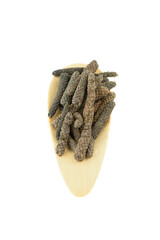 Top view of a serving plate with Long or Pippali peppers on a white background.