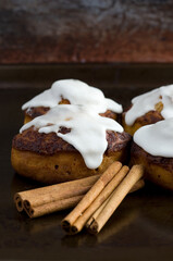 Macro of Cinnamon Buns with White Icing and Cinnamon Sticks