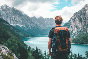 Man with backpack overlooking mountain lake panorama view
