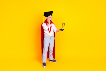 Photo of cheerful happy excited clever smart boy graduate wear red cape isolated on yellow color background